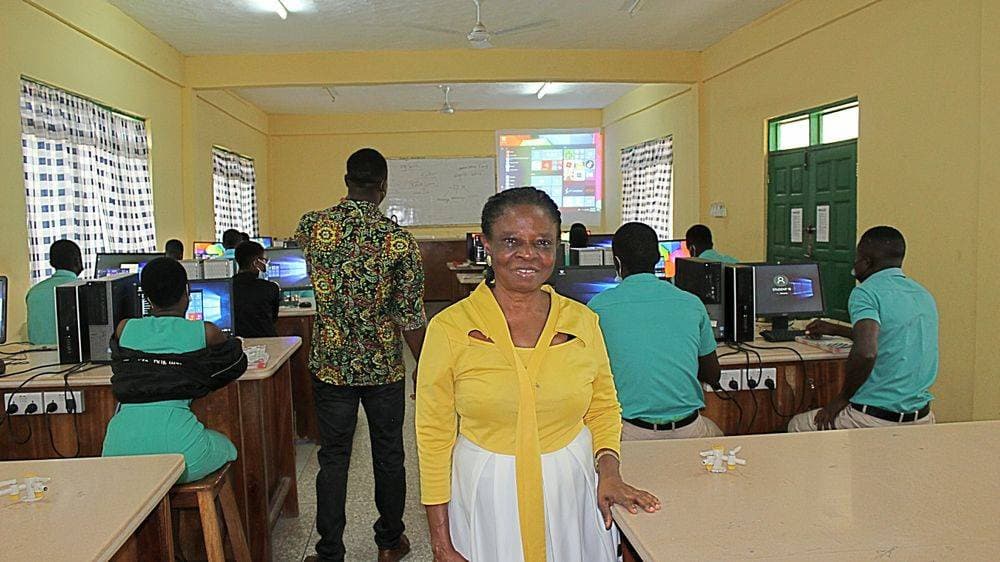 A teacher standing in the lab with students working at HP desktops in the background
